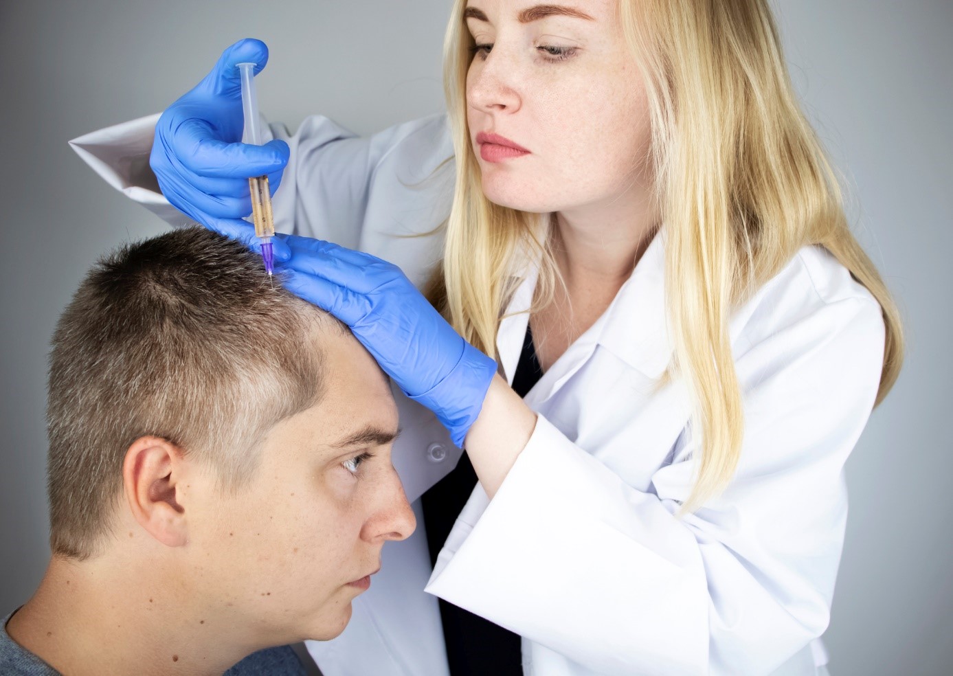 Tratamiento de la caída del cabello, un médico inyecta un medicamento en la cabeza de un señor, un paciente