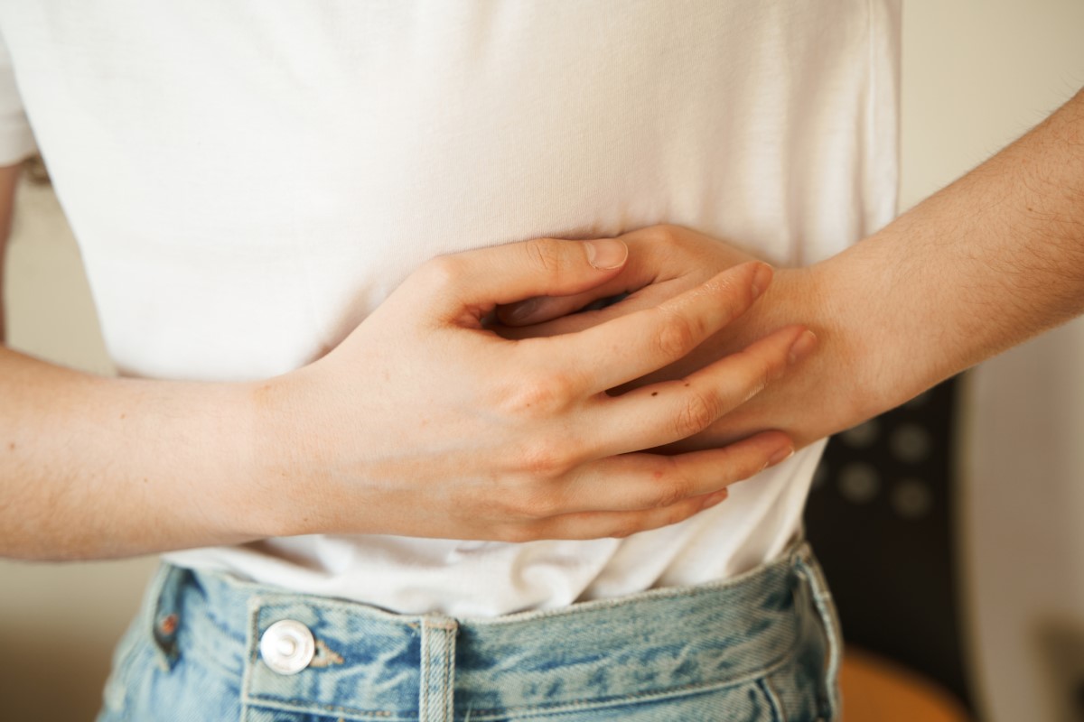 La mujer se sujeta el costado dolorido con las manos, tiene dolor abdominal y otros problemas de salud que pueden indicar obstrucción intestinal.