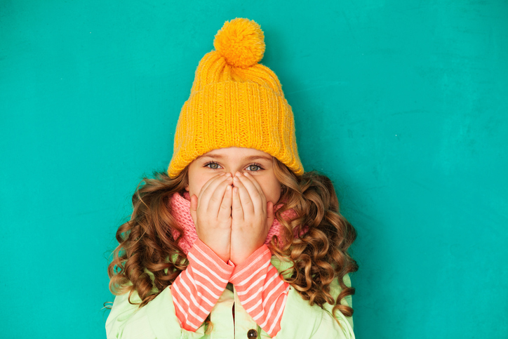 La niña está disfrazada y se cubre la cara con las manos