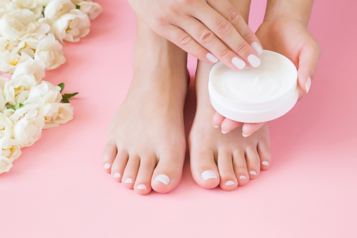 Aplicación de crema para los pies Una mujer se pone crema en los pies con las manos.