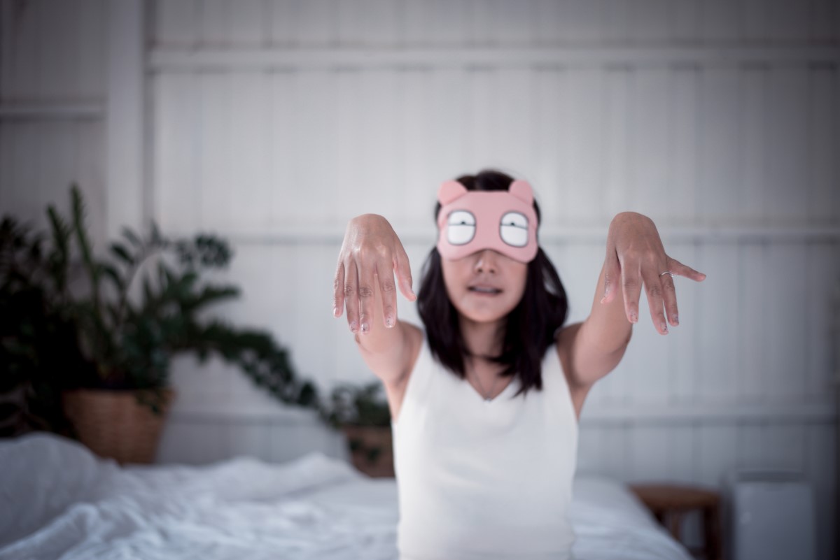 Una mujer malhumorada que se levanta de la cama mientras duerme, una mujer con los ojos tapados.