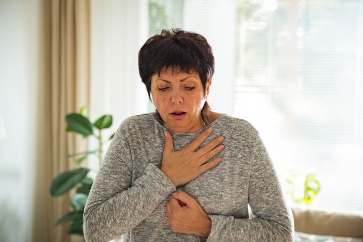 Una mujer tiene dolor en el pecho, como síntoma de cáncer de esófago, sensación de picadura atascada