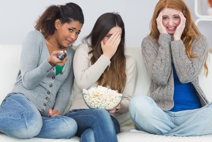 Tres chicas están asustadas, ven una película de miedo, palomitas en un bol