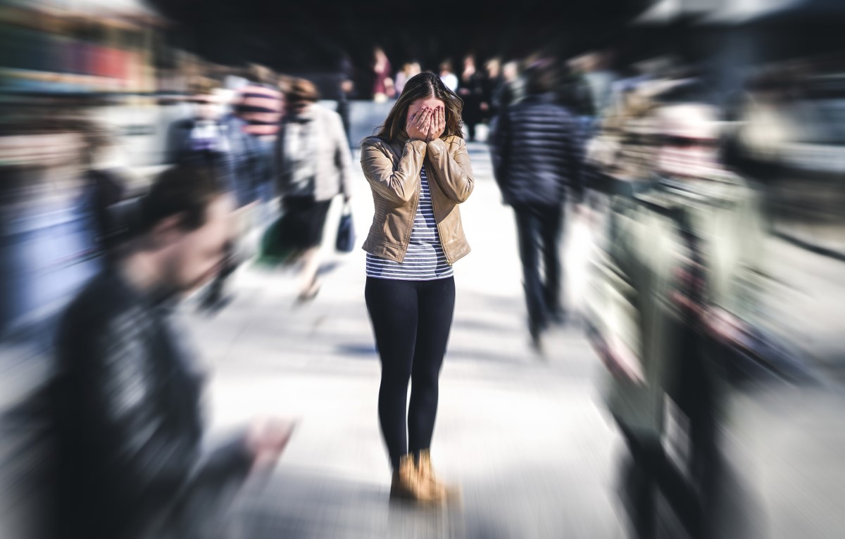 Mujer confundida en medio de una multitud de personas, tiene un problema mental, sensibilidad exagerada a la luz y los sonidos, ruido