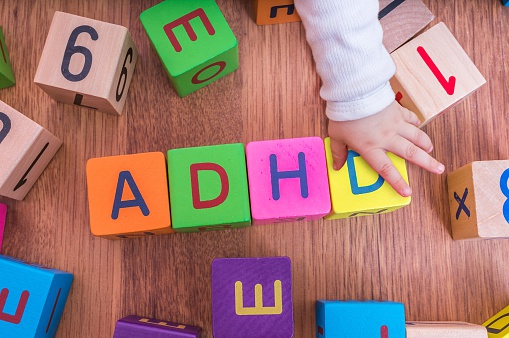 cubos de letras para niños, dispuestos para formar el nombre ADHD, con la mano del niño