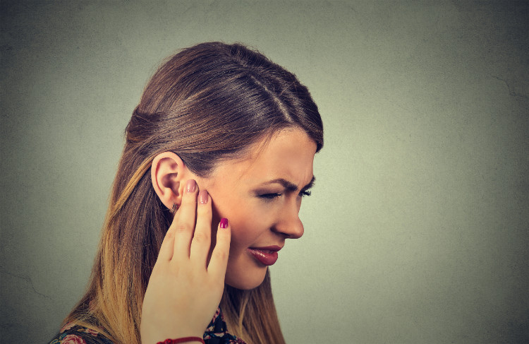 mujer sosteniendo la oreja con la mano