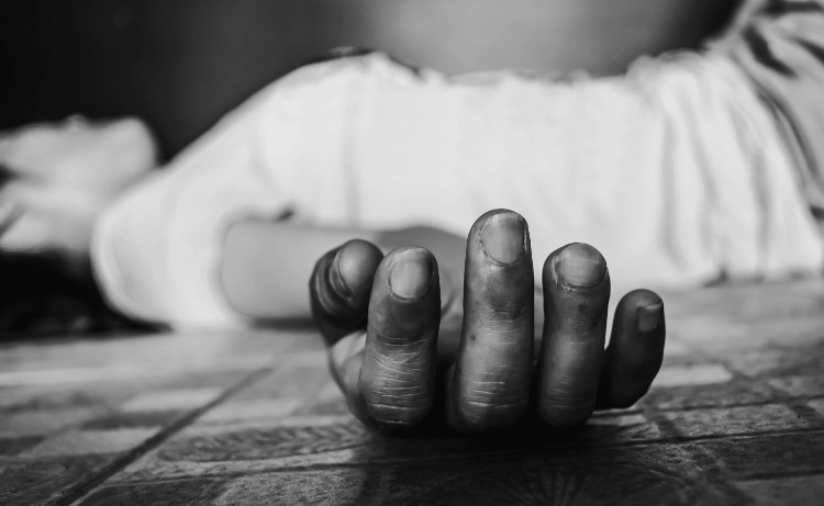 foto en blanco y negro de una mujer con camiseta blanca inconsciente en el suelo