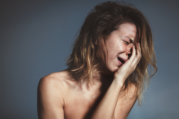 una mujer en un ataque de llanto se sujeta la cara con la mano