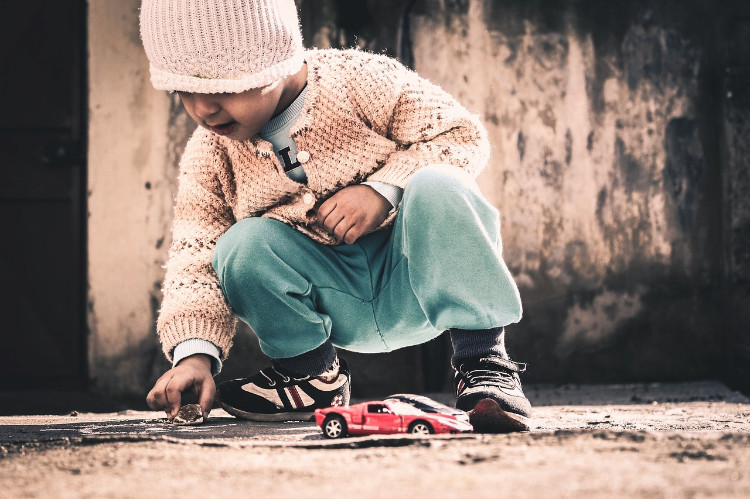 niño jugando con una piedra en la acera