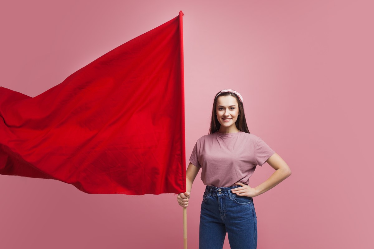 Una mujer sostiene una gran bandera roja a modo de advertencia.