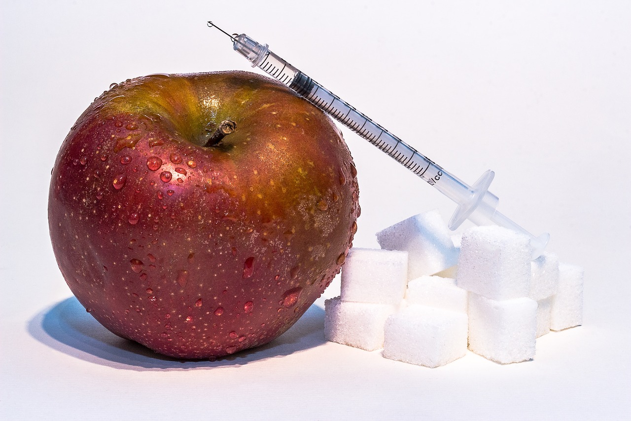 manzana roja, terrones de azúcar y jeringa de insulina