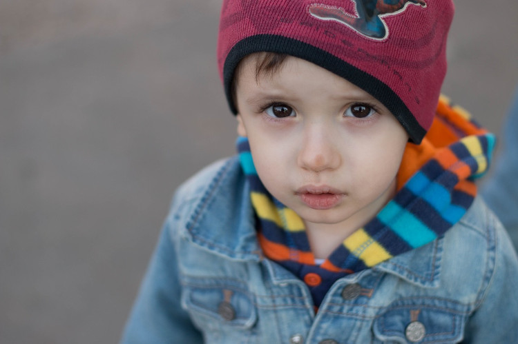 un niño con chaqueta azul y gorra roja mirando al objetivo