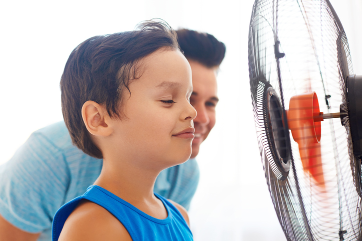 Un niño y su padre delante de un ventilador