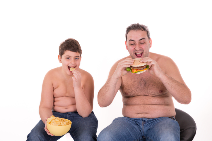 el niño y su padre comen mal, comen hamburguesas, son obesos