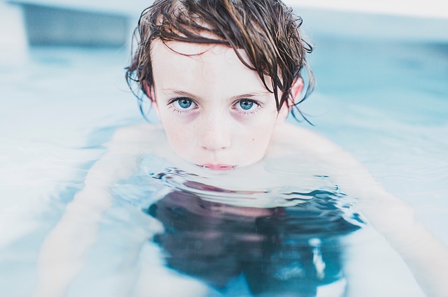 el niño está en la piscina, nadar es una actividad física adecuada