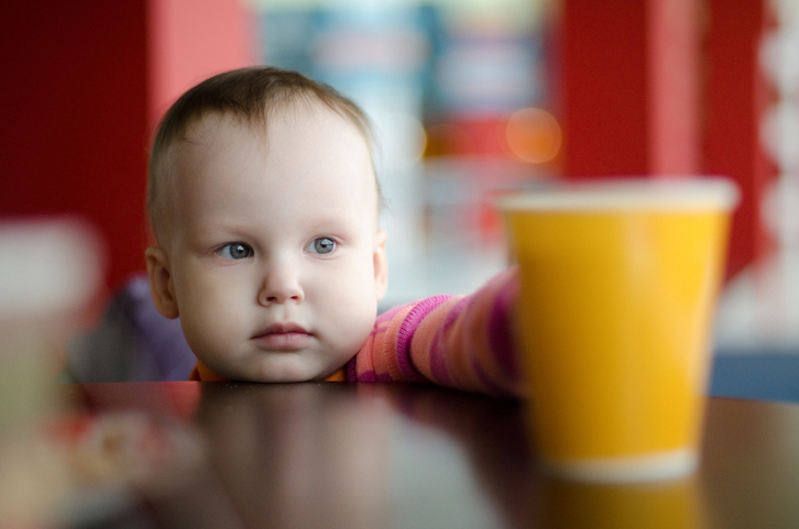 Un niño pequeño coge un vaso de agua de la mesa