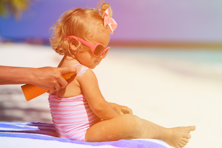 Un niño tomando el sol, su madre le pone crema solar