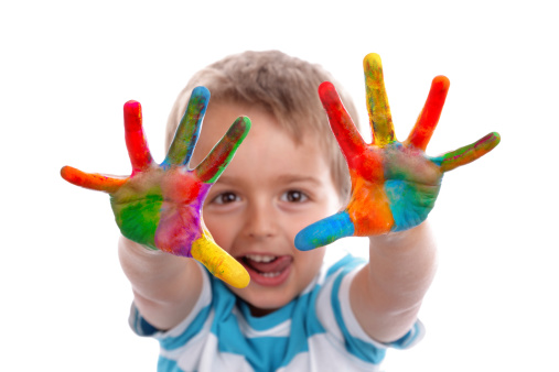 Un niño enseñando sus manos al objetivo manchadas de pintura