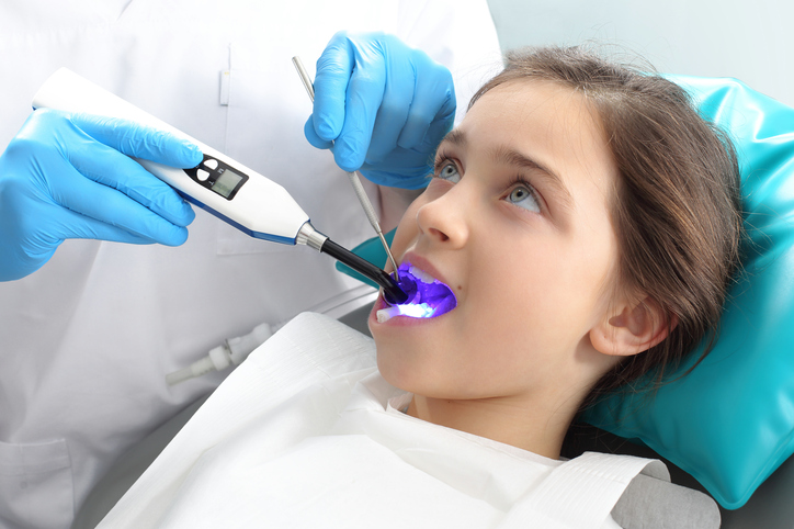 Una niña en el sillón del dentista siendo atendida por el dentista