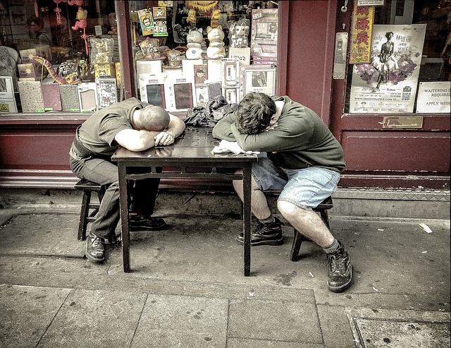 Dos hombres durmiendo en una mesa fuera de la tienda. Es una tienda vieja.