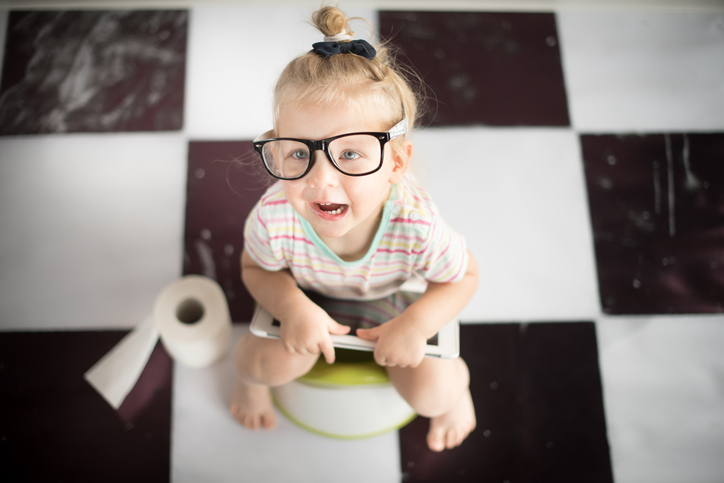 un niño pequeño con gafas de sol sentado en el orinal