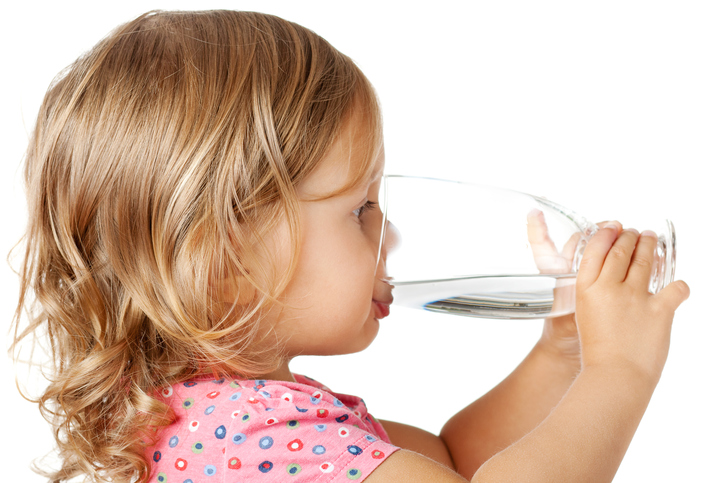 Una niña bebe agua limpia de un vaso