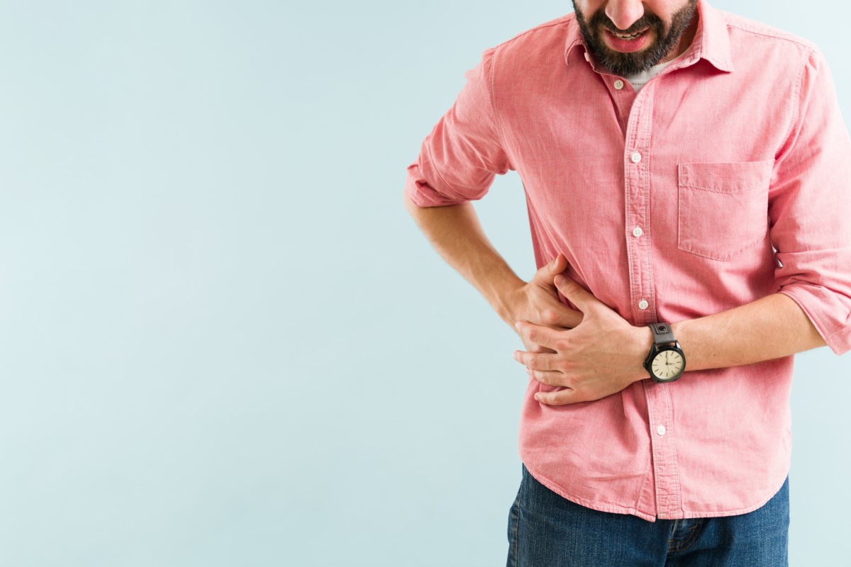 El hombre tiene dolor bajo el arco costal derecho, sujetándose la cadera derecha