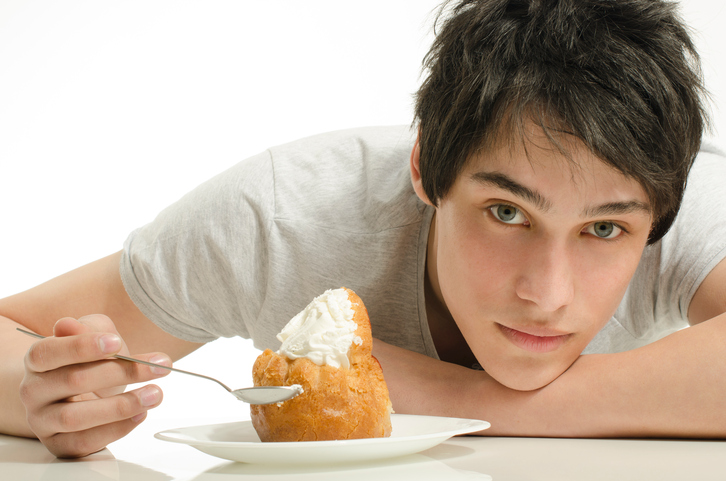 un hombre sentado a la mesa con un postre dulce delante