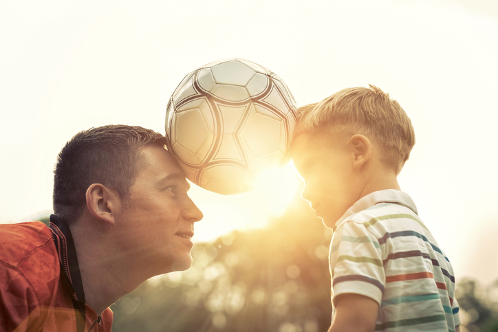 Padre e hijo sostienen el balón entre los dos.