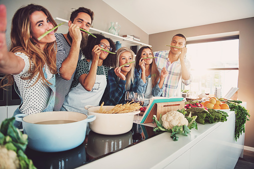 Gente sonriendo mientras preparan la comida. Están detrás de los fogones.