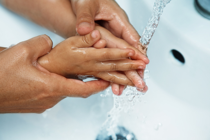 las manos de la madre sobre el lavabo lavar las manos del bebé bajo el grifo