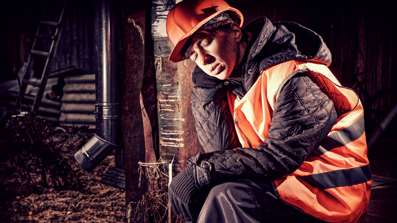 hombre durmiendo en el trabajo con casco rojo y chaleco reflectante