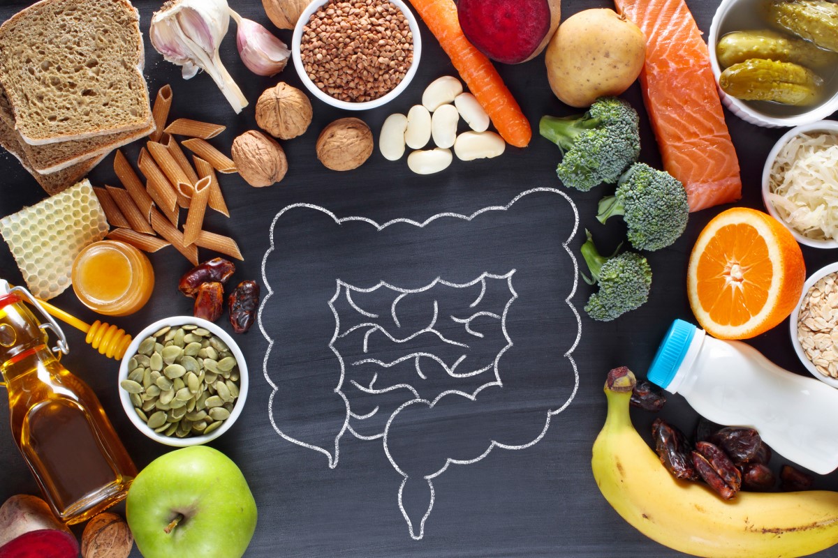 Diversos alimentos, pasta, frutas, verduras, productos lácteos, legumbres y más, y el intestino como ejemplo de la conexión con la salud y los problemas del tracto digestivo.