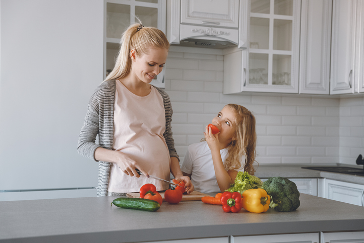 Madre e hija embarazadas preparan una comida sana en la cocina.