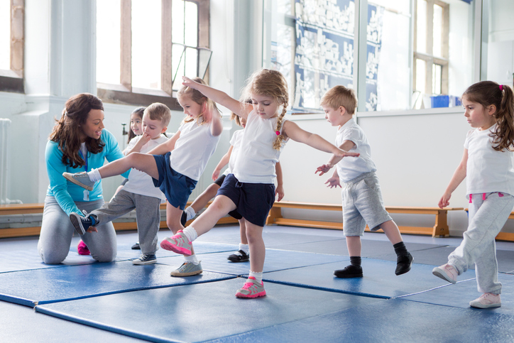 Niños pequeños en el gimnasio, practicando con el profesor.