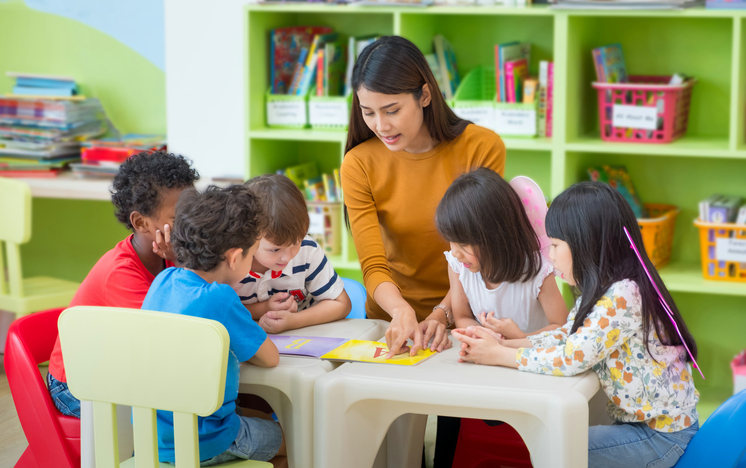 Una maestra de guardería lee un libro a los niños