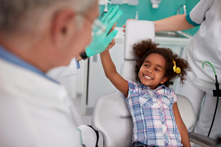 la chica risueña en la silla del dentista con el dentista.