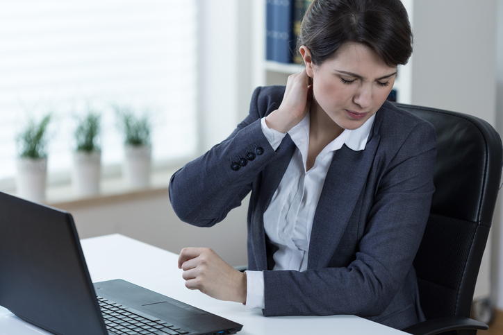 Una mujer tiene dolor en la columna cervical por trabajo prolongado en un ordenador y estar sentada mucho tiempo