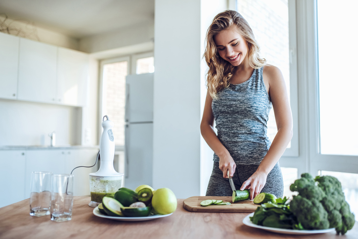 Una joven corta verduras en la cocina.