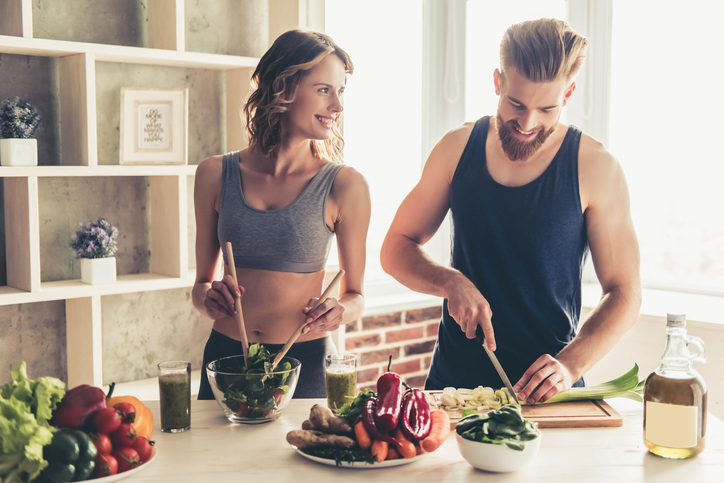 Un hombre y una mujer preparando una comida sana en la cocina.