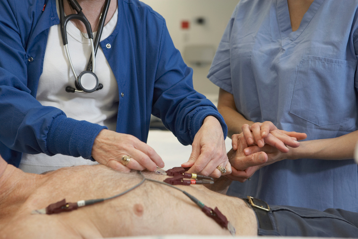 Electrocardiograma del hombre, electrodos en el pecho, dos médicos le examinan