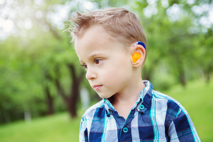 un niño con un audífono de color, tiene una pérdida auditiva