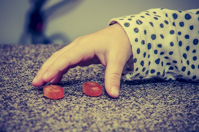 La mano de un niño, dos caramelos rojos, malos hábitos alimenticios