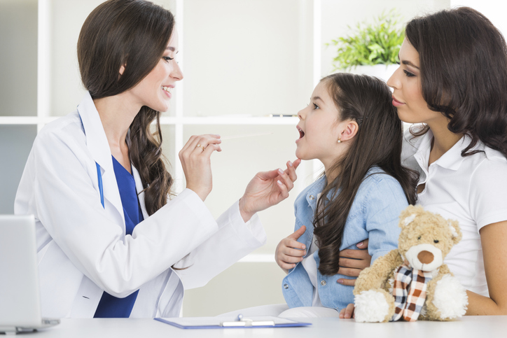 Médico examinando el dolor de garganta de una niña