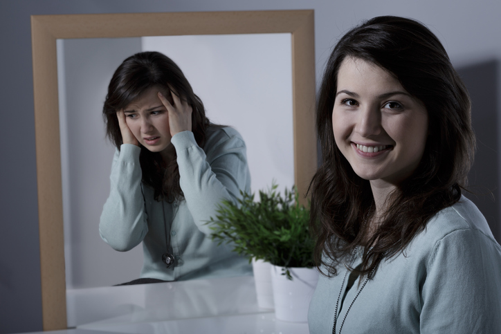 Chica con trastorno afectivo (trastorno afectivo bipolar) o ciclotimia, frente al espejo riendo, episodio maníaco y frente al espejo triste, mal humor, episodio depresivo