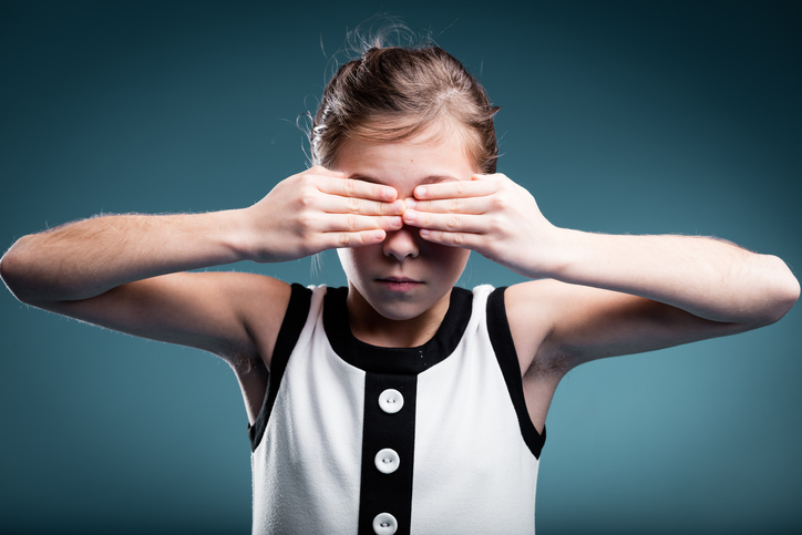 una joven se tapa los ojos en señal de ceguera