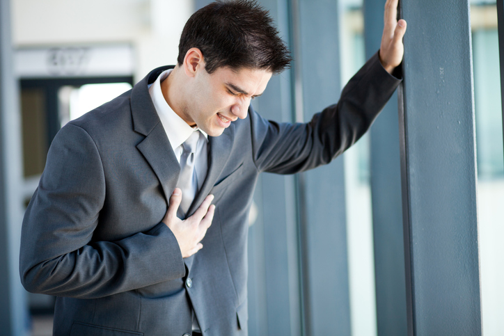 Un hombre joven, un hombre de negocios está en problemas, dolores en el pecho, tal vez él tiene un ataque al corazón o está sobrecargado de trabajo