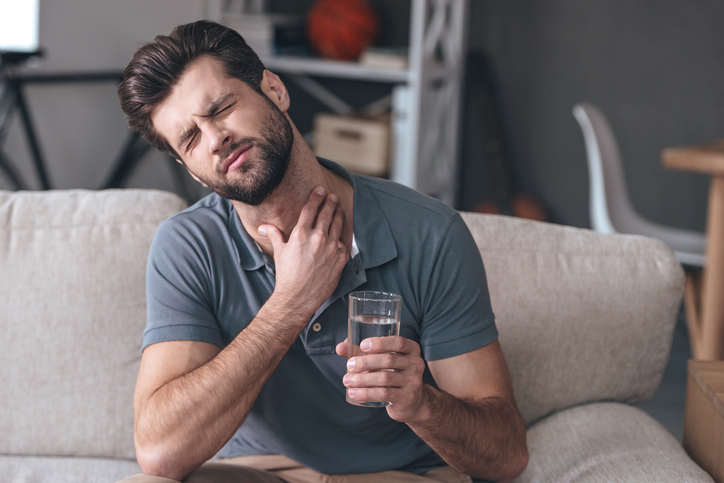 Hombre con dolor de garganta agravado por beber agua