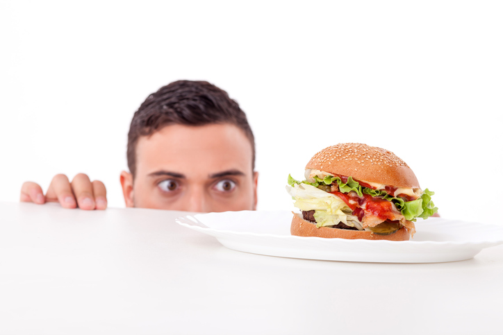 El hombre tiene apetito, hay una hamburguesa en su plato