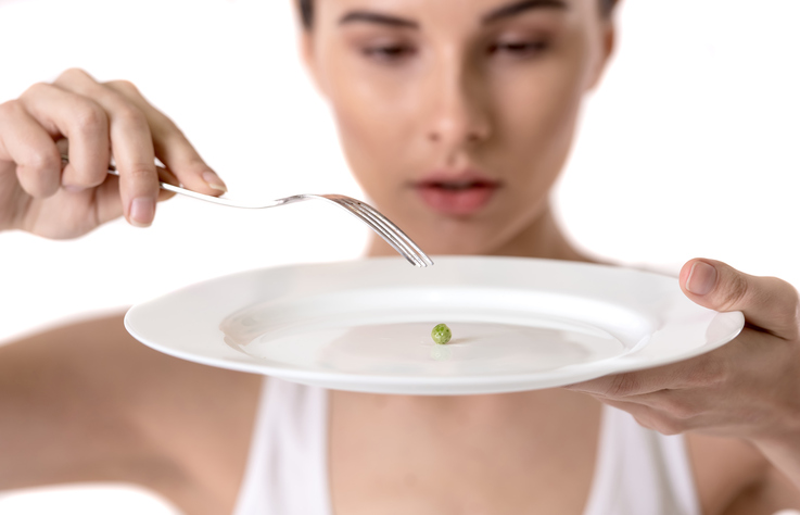 Mujer con guisantes en el plato, restringe la comida